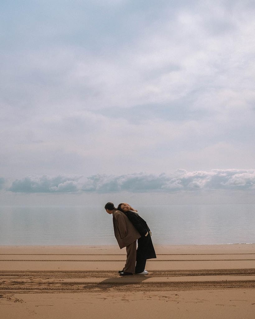 a man standing on top of a sandy beach next to the ocean