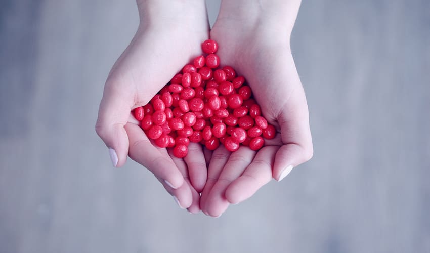 person holding red candies on her palms