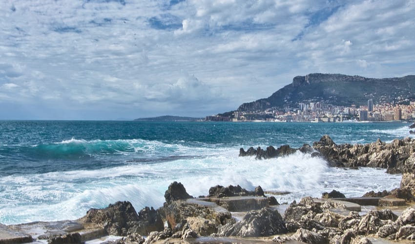 sea waves crashing on rocks under blue and white cloudy sky during daytime