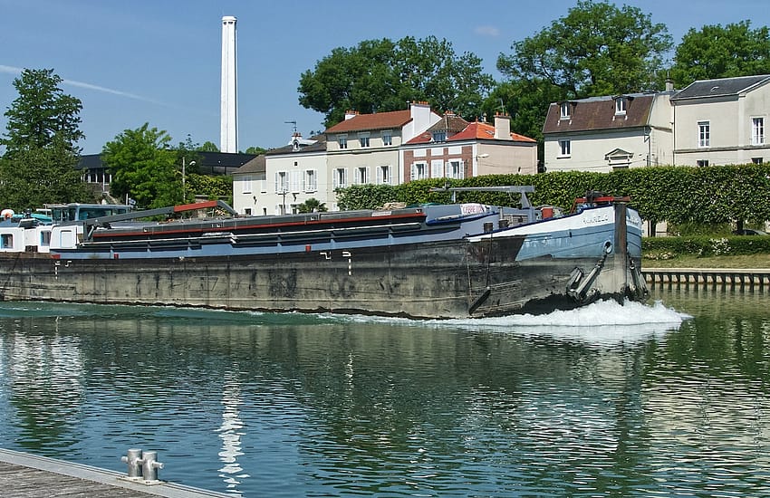 white and brown boat on water near white and brown concrete building during daytime