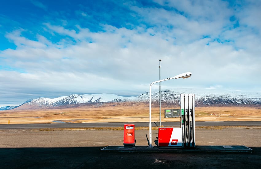 empty gas station near empty road facing snow capped mountain at daytime