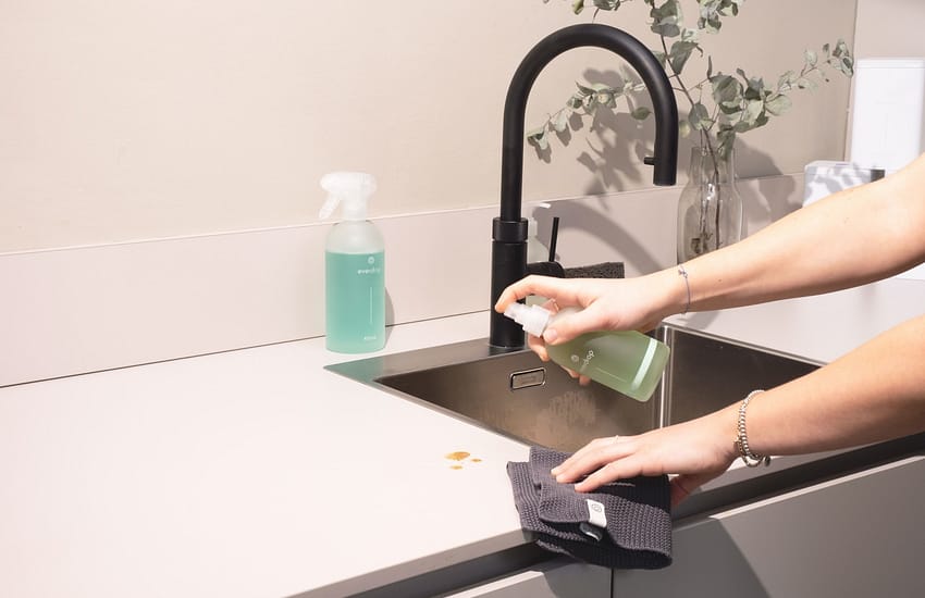 a woman is cleaning a kitchen sink with a rag