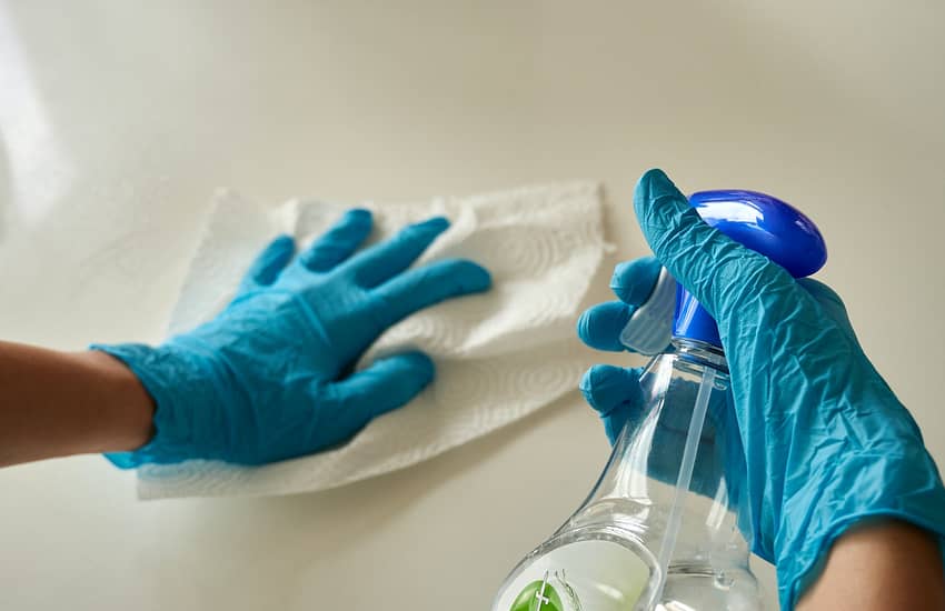 person holding blue textile near clear glass bottle